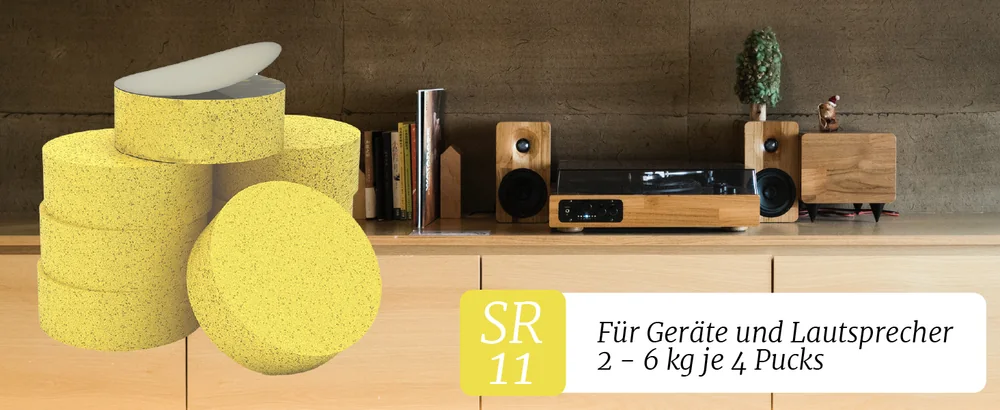 Gelbe Sylo-Pucks vor einem Sideboard mit Plattenspieler und Regallautsprechern